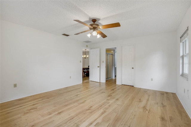 spare room with ceiling fan with notable chandelier, a textured ceiling, and light wood-type flooring