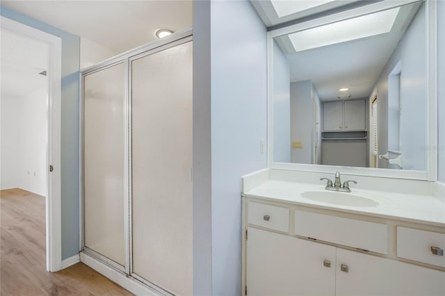 bathroom featuring a skylight, a shower with door, vanity, and hardwood / wood-style floors