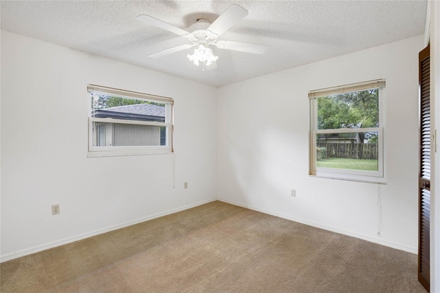 spare room featuring carpet flooring, ceiling fan, a textured ceiling, and a wealth of natural light