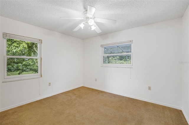 spare room featuring ceiling fan, light colored carpet, and a textured ceiling