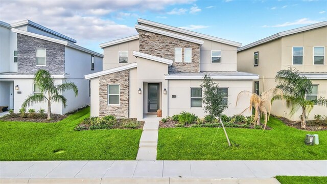 730 Drop Shot Dr, Davenport, FL 33896 - view of front of home featuring stone siding, stucco siding, a front lawn, and a standing seam roof