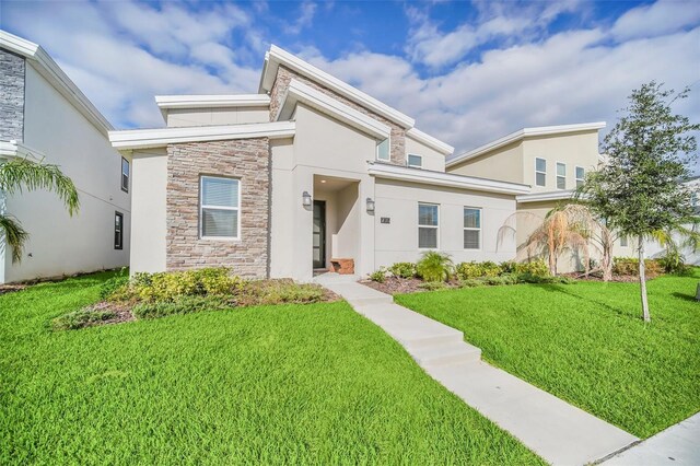 730 Drop Shot Dr, Davenport, FL 33896 - contemporary home featuring stone siding, a front yard, and stucco siding