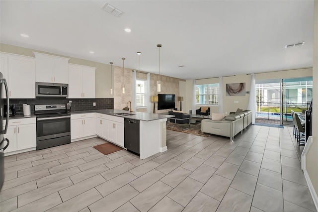 kitchen with kitchen peninsula, white cabinets, hanging light fixtures, range with electric stovetop, and dishwasher