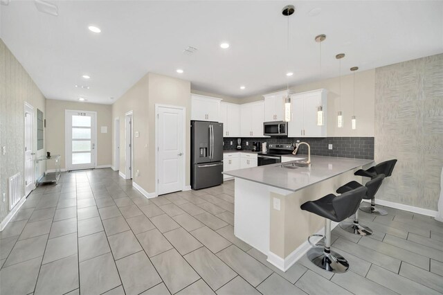 730 Drop Shot Dr, Davenport, FL 33896 - kitchen with stainless steel appliances, a peninsula, a sink, a kitchen bar, and light countertops