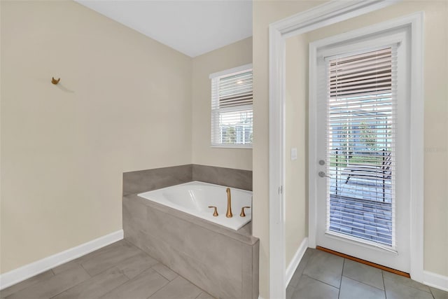 bathroom with tiled tub, a healthy amount of sunlight, and tile patterned flooring