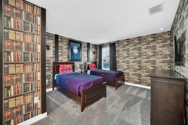 carpeted bedroom with a wood stove, a textured ceiling, and brick wall