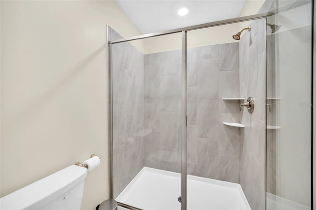 bathroom featuring toilet and a shower with shower door