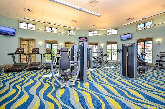 gym featuring a towering ceiling and carpet flooring