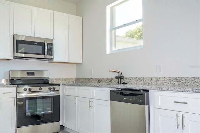 kitchen with white cabinetry, light stone countertops, and stainless steel appliances