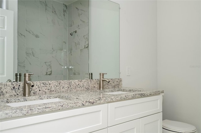 bathroom with vanity, toilet, and tiled shower