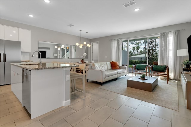 kitchen featuring appliances with stainless steel finishes, light stone counters, sink, white cabinetry, and hanging light fixtures