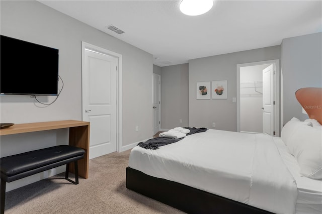 carpeted bedroom featuring a walk in closet and a closet