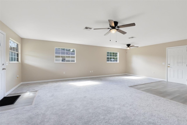 unfurnished living room featuring ceiling fan, light colored carpet, and plenty of natural light