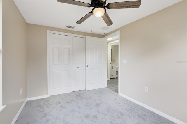 unfurnished bedroom featuring a closet, light colored carpet, and ceiling fan