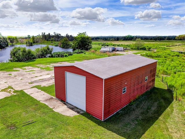 view of outbuilding with a rural view, a lawn, a water view, and a garage