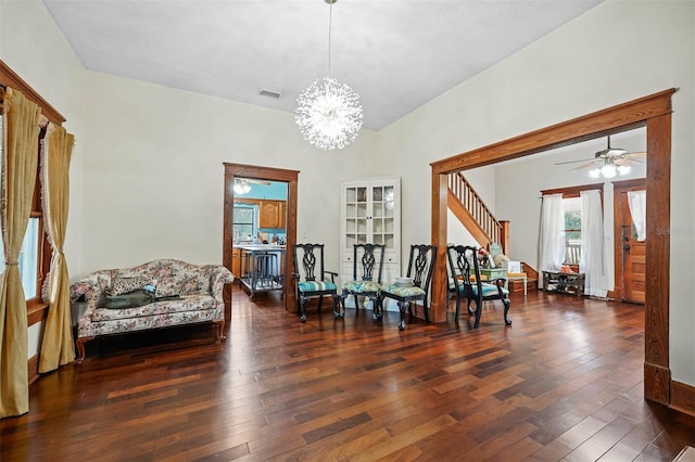 living area with ceiling fan with notable chandelier and dark hardwood / wood-style flooring