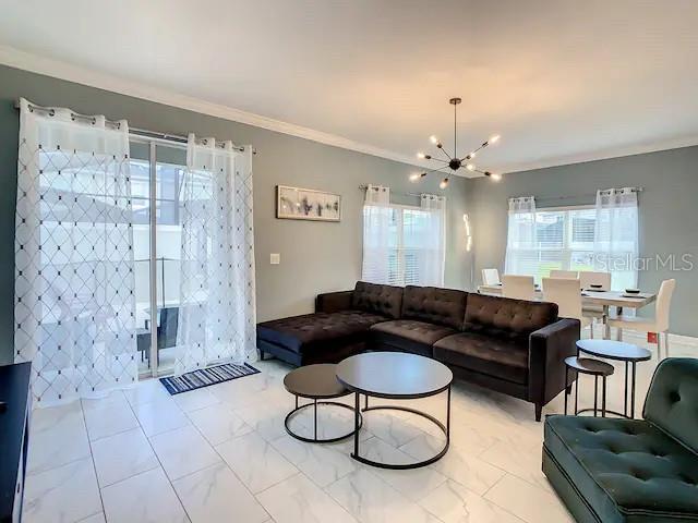 living room with crown molding and a chandelier