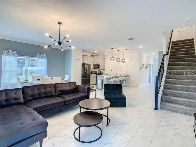 living room featuring crown molding, a chandelier, and sink