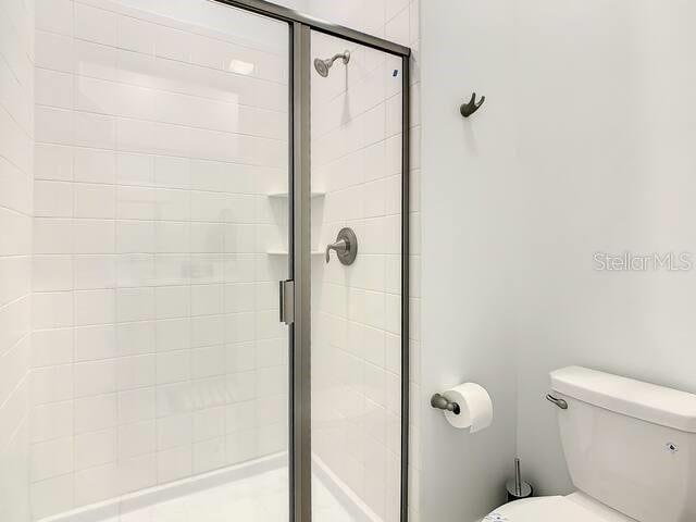 bathroom featuring toilet and an enclosed shower