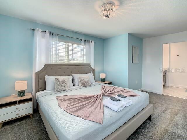 bedroom with ensuite bathroom and carpet flooring