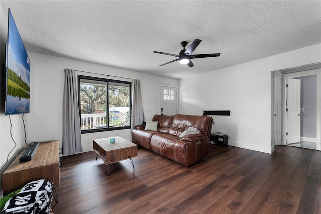 living room featuring ceiling fan, a textured ceiling, and dark hardwood / wood-style flooring