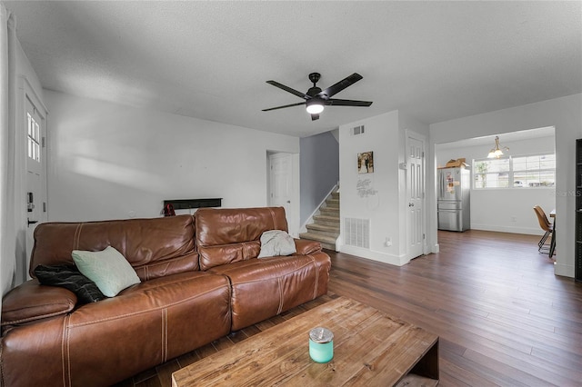 living room with ceiling fan, a textured ceiling, and dark hardwood / wood-style flooring