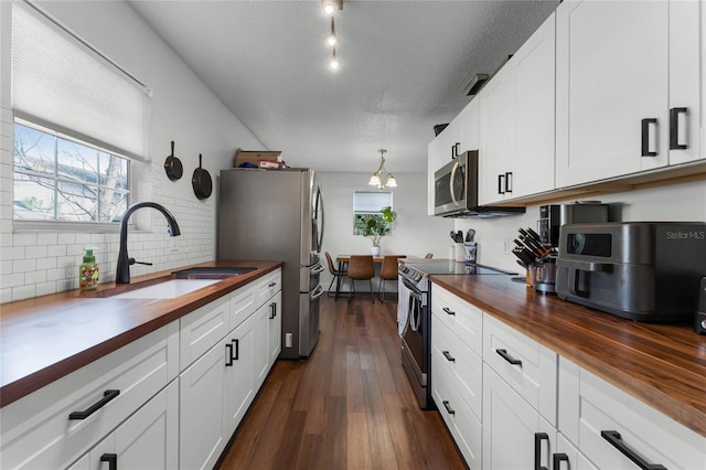 kitchen with dark wood-type flooring, wood counters, sink, white cabinetry, and appliances with stainless steel finishes