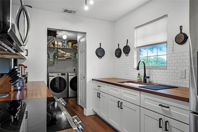 kitchen featuring independent washer and dryer, wood counters, white cabinetry, stainless steel appliances, and dark wood-type flooring