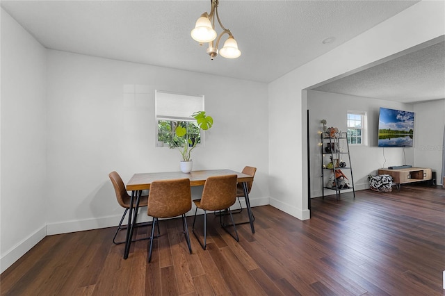 dining space featuring dark wood-type flooring, a notable chandelier, and a textured ceiling