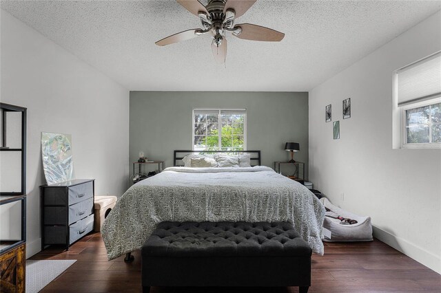 bedroom featuring dark wood-type flooring, a textured ceiling, and ceiling fan