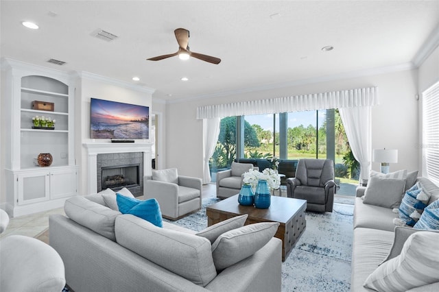 tiled living room featuring built in shelves, a tile fireplace, ceiling fan, and crown molding