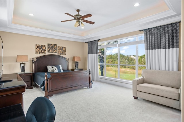 bedroom with ornamental molding, light colored carpet, ceiling fan, and a tray ceiling