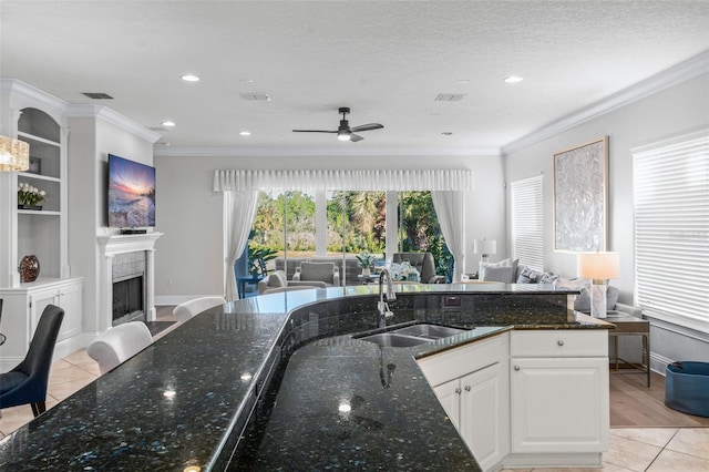 kitchen with crown molding, white cabinetry, light tile patterned floors, sink, and dark stone countertops