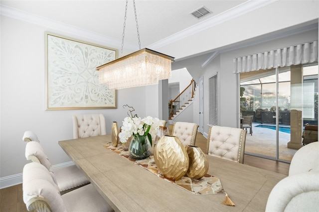 dining space with a chandelier, hardwood / wood-style flooring, and ornamental molding