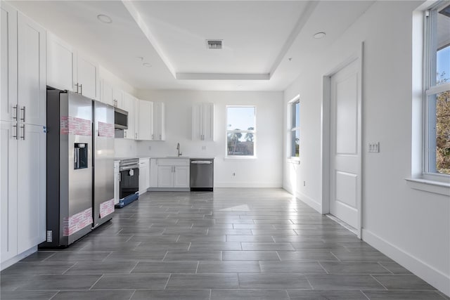 kitchen with stainless steel appliances, white cabinets, sink, dark hardwood / wood-style floors, and a tray ceiling