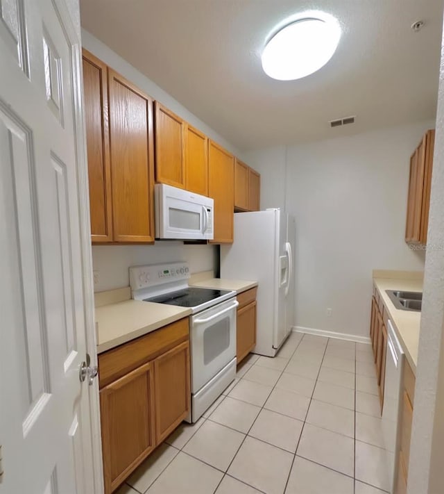 kitchen featuring light tile patterned flooring, sink, and white appliances