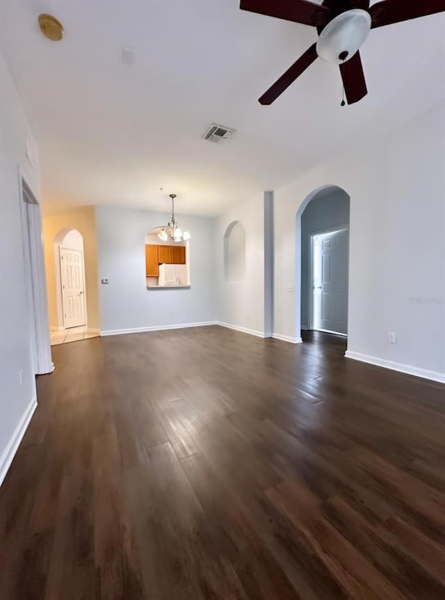 unfurnished living room featuring dark wood-type flooring and ceiling fan with notable chandelier