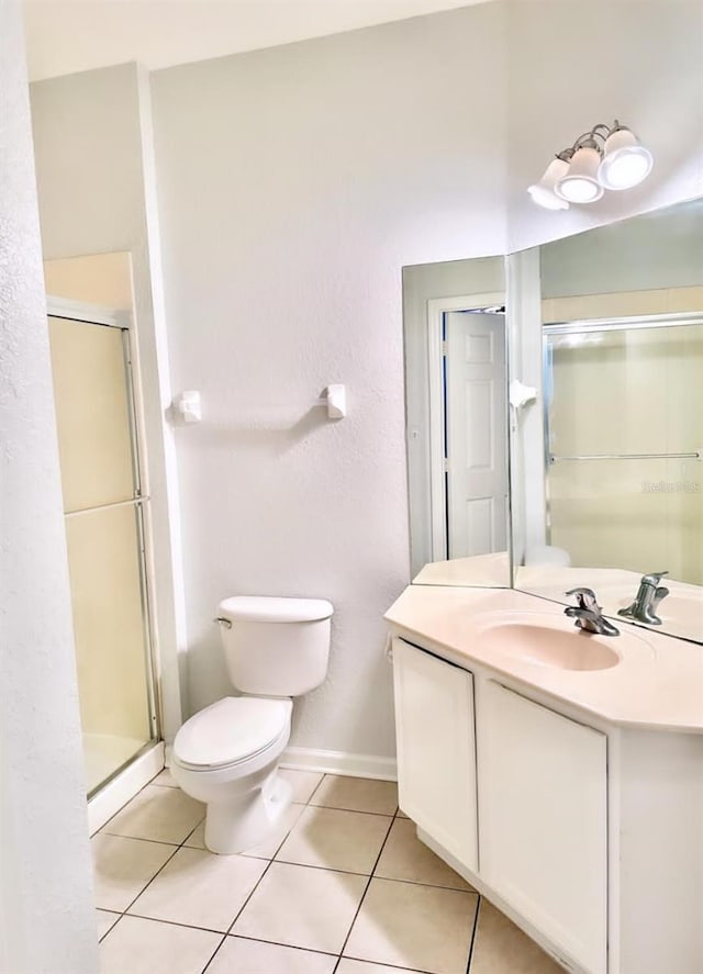 bathroom featuring vanity, toilet, a shower with shower door, and tile patterned floors