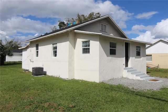 828 Willie Mays Pkwy, Orlando, FL 32811 - back of property featuring cooling unit, stucco siding, entry steps, and a yard