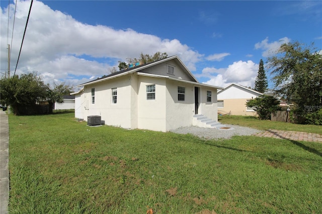 rear view of house featuring central air condition unit and a yard