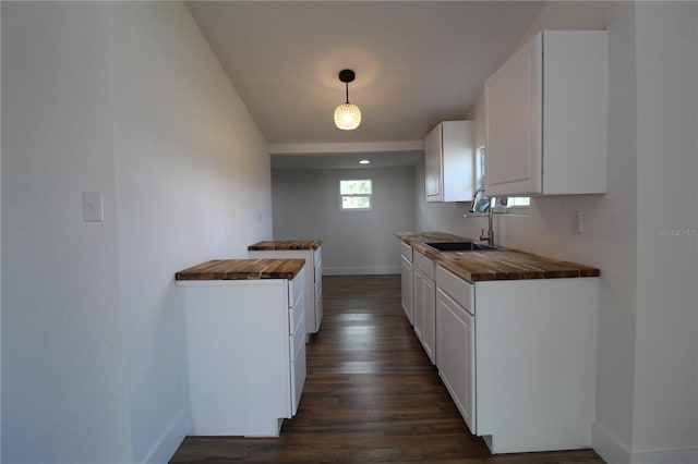 kitchen with dark hardwood / wood-style floors, sink, white cabinets, decorative light fixtures, and butcher block countertops