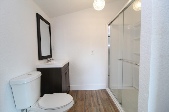 bathroom featuring lofted ceiling, hardwood / wood-style flooring, toilet, a shower with shower door, and vanity