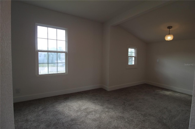 spare room with vaulted ceiling, dark colored carpet, and a healthy amount of sunlight