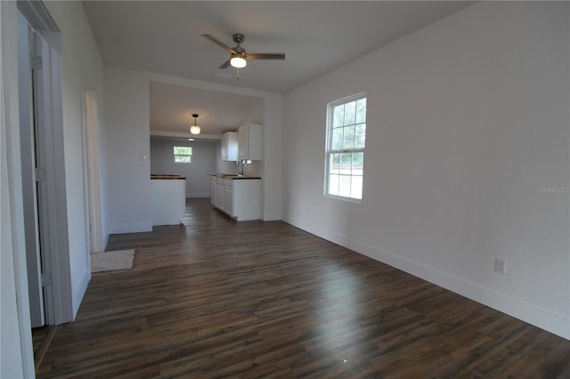 unfurnished living room featuring sink, dark wood-type flooring, and ceiling fan