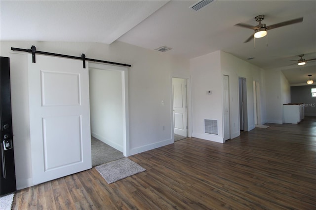 interior space with lofted ceiling, a barn door, ceiling fan, and dark hardwood / wood-style flooring