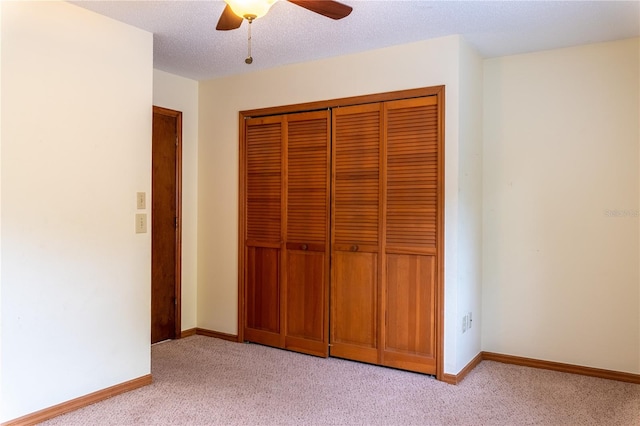 unfurnished bedroom with light colored carpet, ceiling fan, a closet, and a textured ceiling