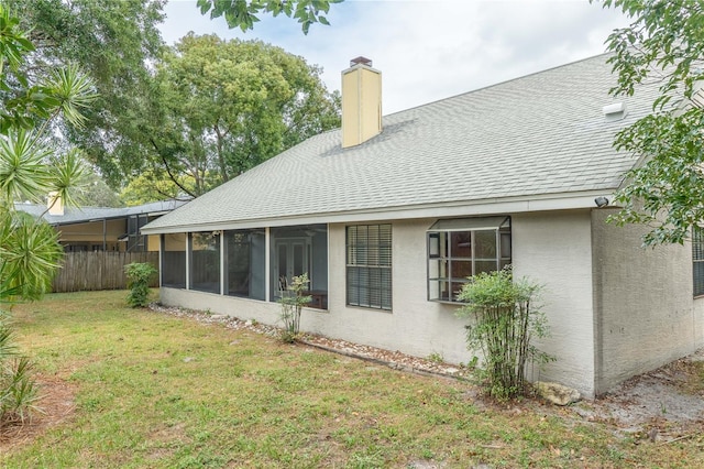 rear view of property with a lawn and a sunroom