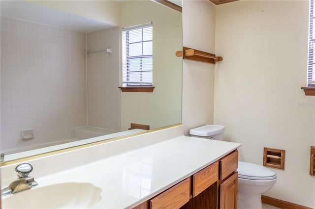 bathroom with toilet, a tile shower, and vanity