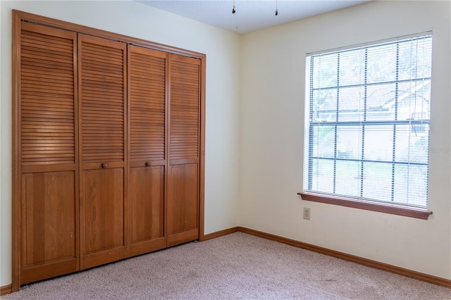 unfurnished bedroom featuring a closet and light carpet