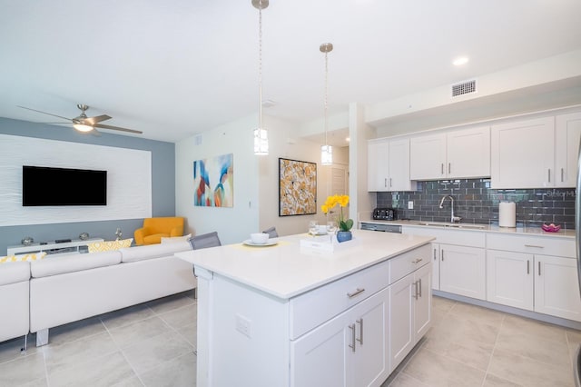 kitchen featuring backsplash, sink, a center island, pendant lighting, and white cabinetry